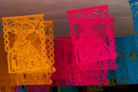 A colorful banner with a woman and a bell on it. The banner is in Spanish. Mexican Day of the Dead tradition, offerings, food, colors, decorations, and papel picado, La Catrina.の写真素材