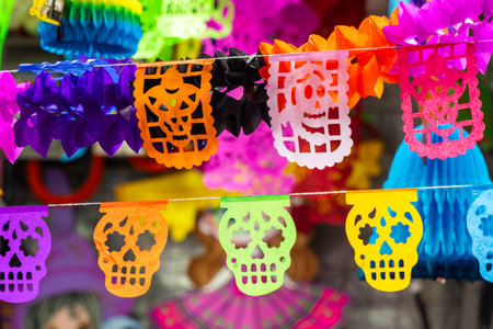 A colorful display of paper skulls and skeletons. The display is made of paper and is very colorful. Mexican Day of the Dead tradition, offerings, food, colors, decorations, and papel picado, La Catrina.の写真素材
