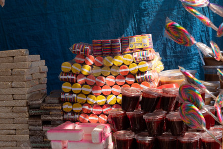 A pile of candy and drinks with a blue background. The candy is in various colors and shapes. Mexican Day of the Dead tradition, offerings, food, colors, decorations, and papel picado.の写真素材
