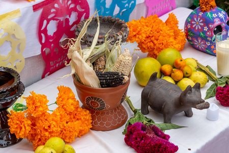A table is decorated with a variety of fruits and vegetables, including oranges, apples, and corn. Mexican Day of the Dead tradition, offerings, food, colors, decorations, and papel picado, La Catrina.の写真素材
