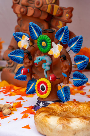 A beautifully decorated vase with a snake and birds is placed on a table. Mexican Day of the Dead tradition, offerings, food, colors, decorations, and papel picado.の写真素材