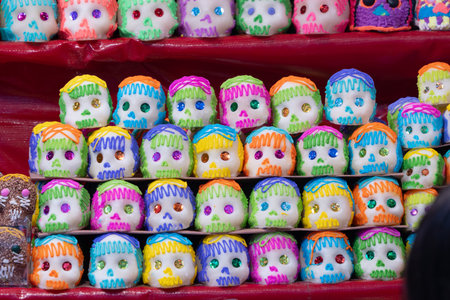 A collection of painted skulls, each with its own unique color scheme and design, are arranged in a . Mexican Day of the Dead tradition, offerings, food, colors, decorations, and papel picado, La Catrina.の写真素材