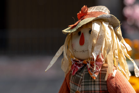 A scarecrow with a hat and a red nose stands in front of a fence. The image has a spooky. The image has offerings, food, colors, decorations, and papel picado.の写真素材