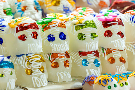 A collection of sugar skulls with various colors and designs, arranged in a way that they appear to . Mexican Day of the Dead tradition, offerings, food, colors, decorations, and papel picado, La Catrina.の写真素材
