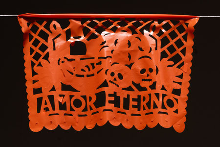 A colorful paper lantern with skulls and flowers on it, and the words "Amor Eterno" written in black. Mexican Day of the Dead tradition, offerings, colors, decorations, and papel picado, La Catrina.の写真素材