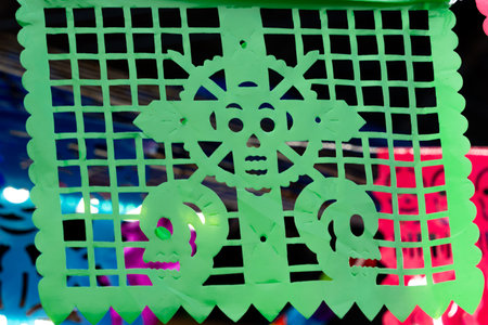 A green paper with a skull on it. The skull is surrounded by a circle. Mexican Day of the Dead tradition, offerings, food, colors, decorations, and papel picado, La Catrina.の写真素材