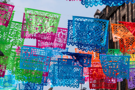 A colorful display of paper flags with the word on them. The flags are hanging from a wire. Mexican Day of the Dead tradition, offerings, food, colors, decorations, and papel picado, La Catrina.の写真素材