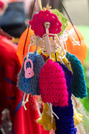 A colorful assortment of knitted items, including a skeleton, are hanging from a string. Mexican Day of the Dead tradition, offerings, food, colors, decorations, and papel picado, La Catrina.の写真素材