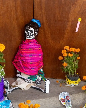 A skeleton is sitting on a step with a pink blanket draped over it.Mexican Day of the Dead tradition, offerings, food, colors, decorations, and papel picado, La Catrina.の写真素材