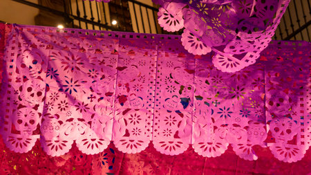 A beautiful pink and purple paper lantern with a floral and skull pattern is hanging. Mexican Day of the Dead tradition, offerings, food, colors, decorations, and papel picado, La Catrina.の写真素材