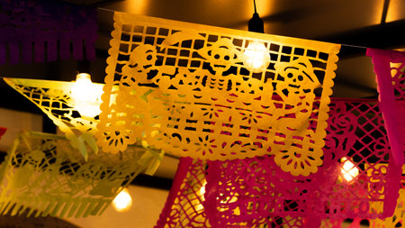 A bunch of colorful paper lanterns hanging from the ceiling. The lanterns are in various colors. Mexican Day of the Dead tradition, offerings, food, colors, decorations, and papel picado, La Catrina.の写真素材