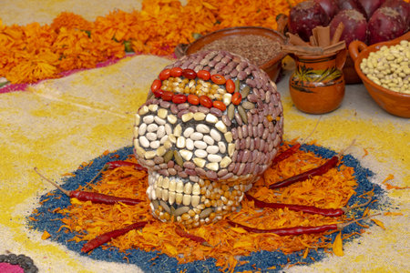 A skull made of beans and peppers is placed on a table with other items. Mexican Day of the Dead tradition, offerings, food, colors, decorations, and papel picado.の写真素材