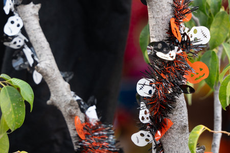 A tree branch is decorated with skulls and bones. The branch is covered in black. Mexican Day of the Dead tradition, offerings, food, colors, decorations, and papel picado, La Catrina.の写真素材