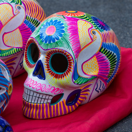 A colorful skull with a bird on it. The skull is painted with bright colors and has a bird on it. Mexican Day of the Dead tradition, offerings, food, colors, decorations, and papel picado, La Catrina.の写真素材