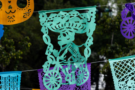 A festive decoration featuring a skeleton dressed in a sombrero and riding a bicycle. Mexican Day of the Dead tradition, offerings, food, colors, decorations, and papel picado, La Catrina.の写真素材