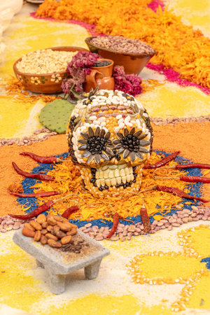A skull is placed on a table with other items, including a bowl of nuts and a bowl of beans. Mexican Day of the Dead tradition, offerings, food, colors, decorations, and papel picado, La Catrina.の写真素材