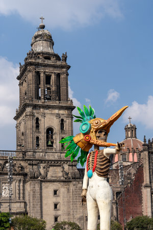 A skeleton dressed in a costume with a bird head and a skeleton's face is standing in front of a cathedral. Mexican Day of the Dead tradition, offerings, food, colors, decorations, and papel picado, La Catrina.の写真素材