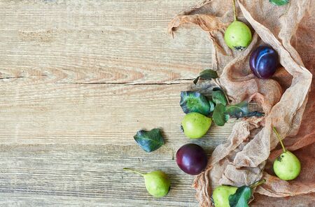 Autumnal flat empty design mocup with pears, leaves and plum on textured coral textile on wood, closeup, background texture, decorative conceptの写真素材