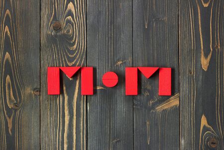 Mom word from red toy bricks flat on dark textured wooden background, copy space for your design, from above top view, Mother's day zero waste conceptの写真素材