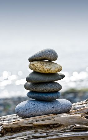 Balanced stones on driftwood along the beachの写真素材