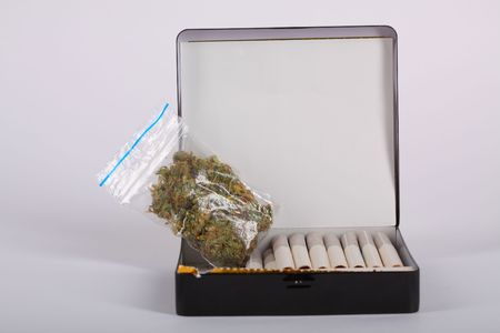 Cigarettes and plastic bag of marijuana in the boxの写真素材