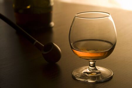 A glass with some brandy and pipe.の写真素材