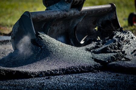 Laying fresh asphalt on construction site on a road
