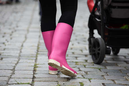 Young woman with pink rubber boots walks on a streetのeditorial素材