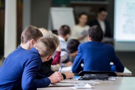 Brainstorming, young students of 18-20 years old, vividly discuss the lecture of teachers at the table, take an exam, write and answer control questions, get credit and gradesの写真素材