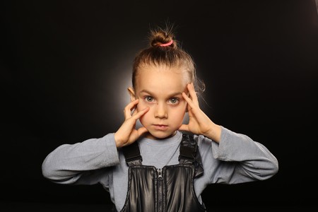 Ukrainian girl, 5-9 years old, in overalls, holds hands at a serious, beautiful face with a straight...