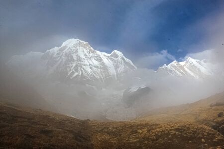 Amazing autumn view with snow-covered mountains and white fog over the lakes with blue skyの写真素材