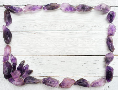 Frame of amethyst beads on white wooden background, top view.の写真素材