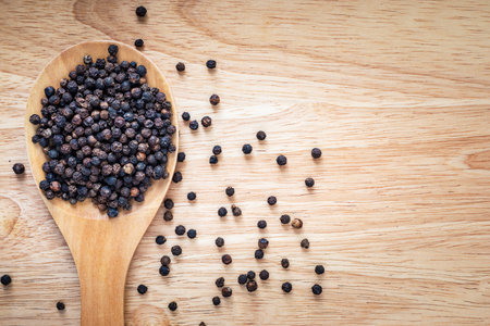 Black pepper in wooden spoon on wooden background with copy space for your text.の写真素材