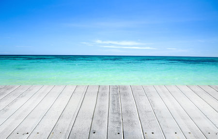 Wooden deck on tropical beach with turquoise sea and blue skyの写真素材
