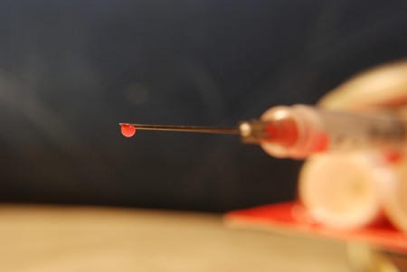 Close-up of a needle and syringe with a drop of thinned blood.の写真素材