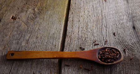 Wooden spoon with a clove. Background with old natural boards.の写真素材
