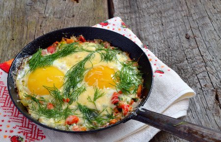Fried eggs with greens, vegetables and cheese on a frying pan の写真素材