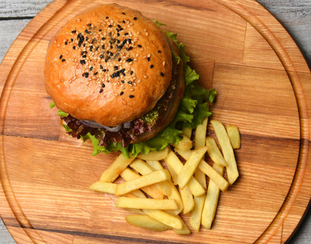 Burger with French fries on a wooden board. Top view. Fast food.の写真素材