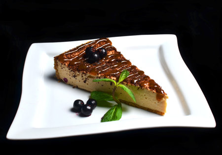 Chocolate cheesecake with blueberries and mint on a plate isolated on a black background.の写真素材