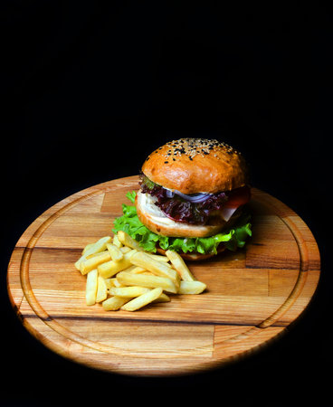 Burger with French fries on a wooden board. Fast food.の写真素材
