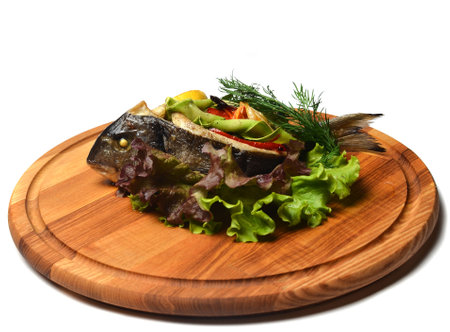 Baked fish with vegetables on a wooden board.の写真素材