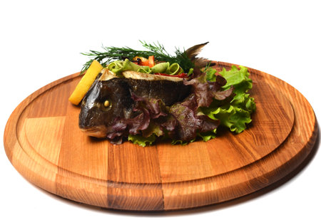 Baked fish with vegetables on a wooden board.の写真素材