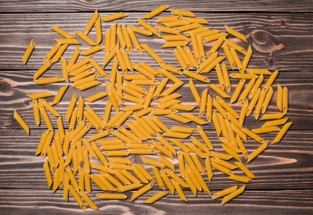 A handful of macaroni on a wooden table closeup.の写真素材