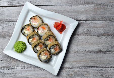 Sushi roll banzai close up. Hot roll philadelphia with shrimp on a plate on a wooden table.の写真素材