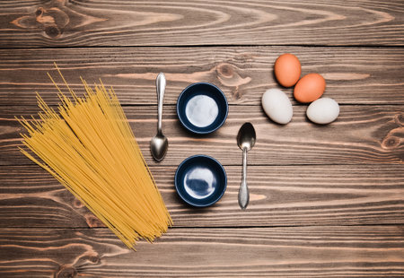 Bowls for cooking, pasta, eggs on a wooden table. The cooking process.の写真素材
