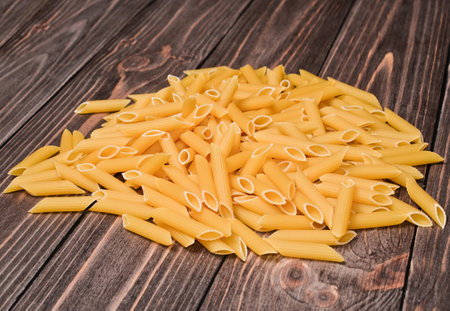A handful of macaroni on a wooden table closeup.の写真素材