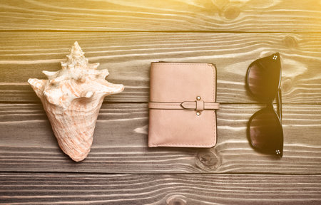 Concept of travel. Shell, purse, sunglasses on a wooden surface. Top view. Flat lay.の写真素材