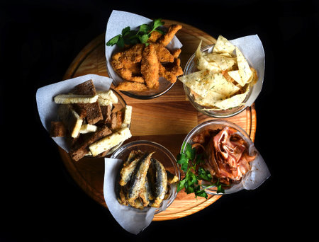 Snacks to beer in glassware on a wooden board. Chips, snacks, rusks, dried meat, fried fish.の写真素材