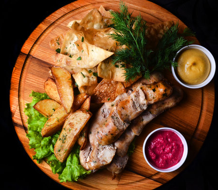 Snacks to beer on a wooden board. Bavarian fried sausages, fried potatoes, chips isolated on a black background. Top view.の写真素材