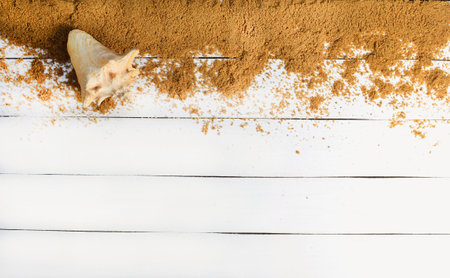Sand and seashell on a white wooden surface. The concept of relaxing at sea. Summer beach season is open! Top view.の写真素材